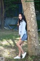 A young woman leaning against a tree in a park.