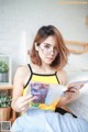 A woman sitting on a bed reading a book.