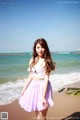 A woman standing on a beach next to the ocean.