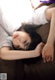 A woman laying on top of a brown couch.