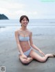 A woman in a bikini sitting on the beach.