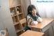 A woman sitting at a desk in a classroom.