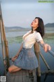 A woman in a white shirt and plaid skirt posing on a wooden dock.