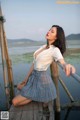 A woman in a white shirt and blue plaid skirt posing on a wooden dock.