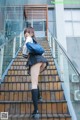 A woman in a school uniform is standing on some stairs.