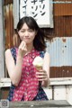 A woman eating an ice cream cone in front of a building.