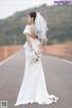 A woman in a wedding dress standing on a road.