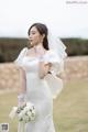 A woman in a wedding dress holding a bouquet of flowers.