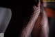 A close up of a woman's legs in fishnet stockings.