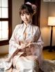 A woman in a pink kimono sitting on a bed.