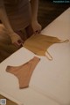 A woman in a tan dress is putting on a tan underwear.