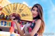 A woman in a cheongsam holding a yellow fan.