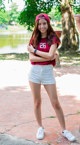 A woman in a red shirt and white shorts posing for a picture.