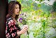 A woman holding a bunch of flowers next to a tree.