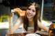 A woman sitting at a table eating a piece of bread.