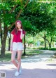 A woman in a red shirt and white shorts posing for a picture.