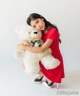 A woman in a red dress holding a white teddy bear.