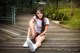 A woman sitting on a wooden boardwalk in a park.