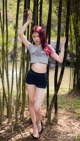 A woman with red hair standing in front of a bamboo forest.