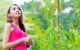 A woman in a pink tank top standing in a field.