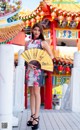 A woman standing in front of a chinese temple holding a fan.