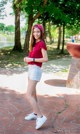 A woman in a red shirt and white shorts posing for a picture.