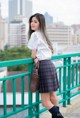 A woman in a school uniform standing on a bridge.