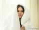 A woman wrapped up in a white blanket.