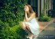 A woman in a white dress sitting on the ground.