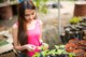 A woman in a pink tank top is looking at a plant.