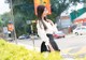 A woman in a white blouse and black skirt standing on the street.