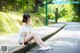 A woman sitting on the side of a road with her legs crossed.