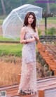 A woman standing on a wooden bridge holding an umbrella.