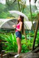 A woman standing in the rain holding an umbrella.