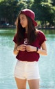 A woman in white shorts and a maroon shirt is standing by the water.