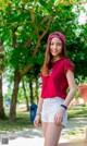 A woman in a red shirt and white shorts posing for a picture.