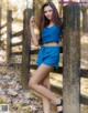 A woman leaning against a wooden fence in the woods.