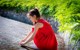 A woman in a red dress crouching down on the ground.