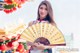 A woman in a chinese dress holding a fan.