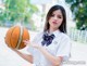 A woman in a school uniform holding a basketball.