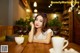 A woman sitting at a table with a cup of coffee.