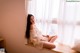 A woman sitting on a window sill in a white dress.