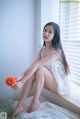 A woman sitting on a window sill holding a flower.