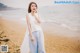 A woman standing on a beach next to the ocean.