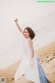 A woman in a white dress standing on a beach.