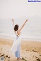 A woman standing on a beach with her arms outstretched.