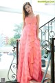 A woman in a pink dress standing on a balcony.