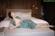 A woman laying on a bed in a green dress.