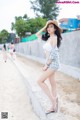 A woman in a straw hat is posing on the beach.