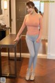 A woman in a pink top and gray leggings posing for a picture.